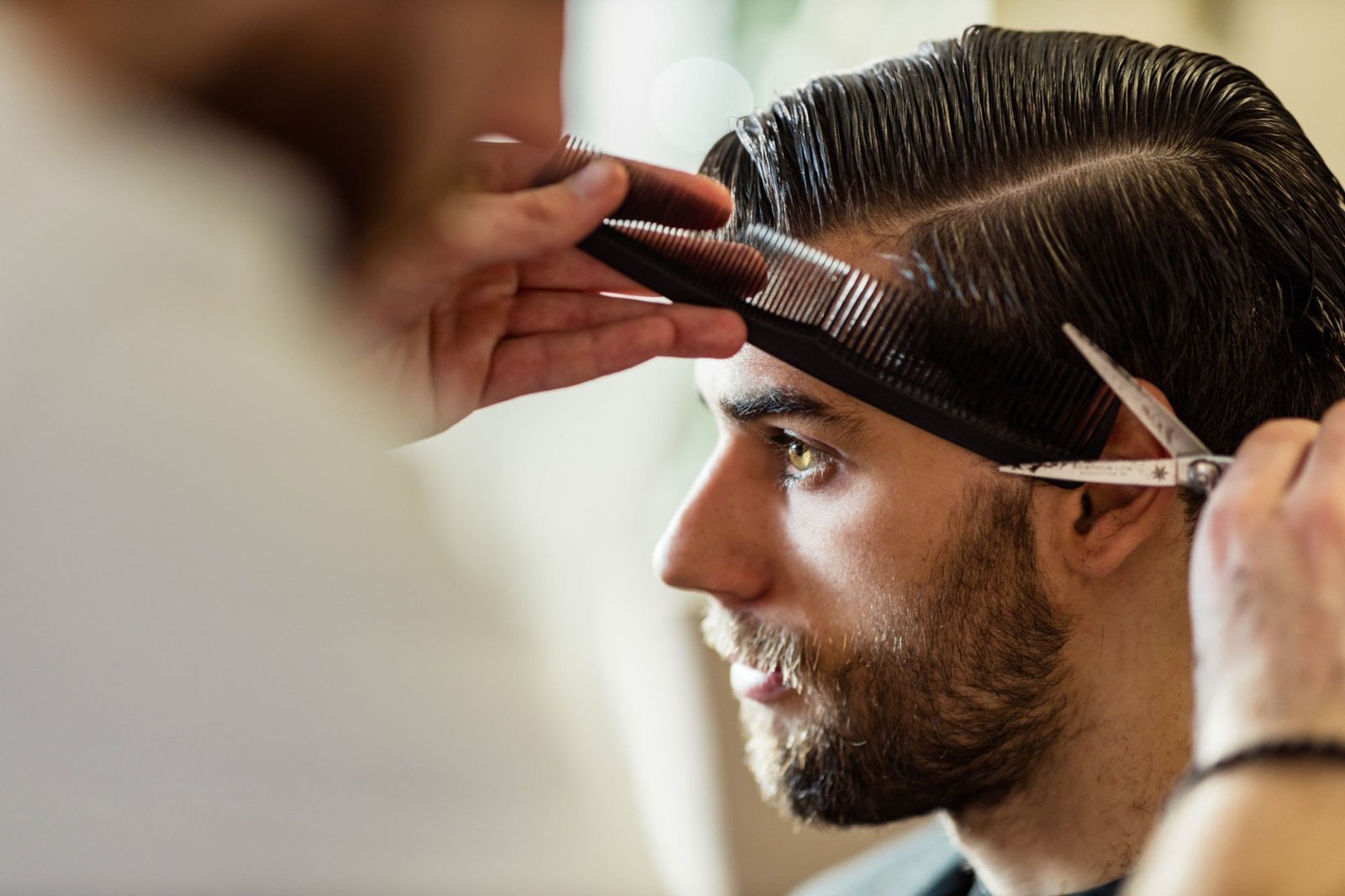Young man having his hair styled by a barber at home. Copy space.